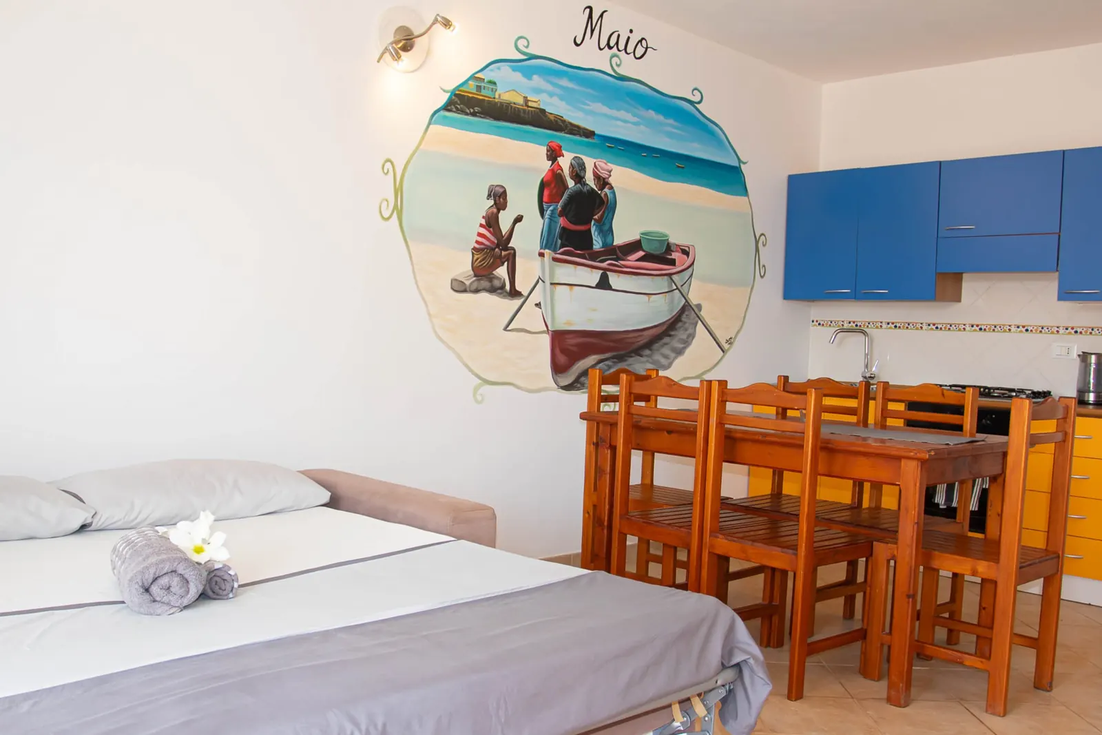 Maio — bed with the Maio mural and kitchen